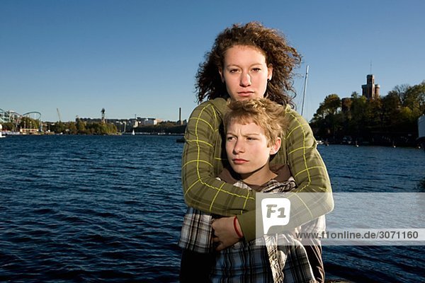 Schwester umarmt ihr Bruder mit Wasser im Hintergrund Schweden.