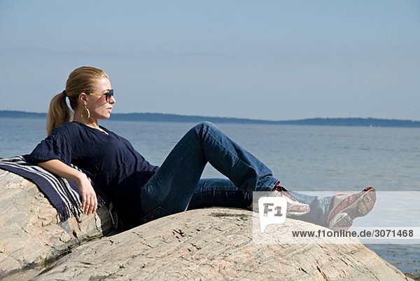 Eine junge Frau sitzend am Meer Schweden