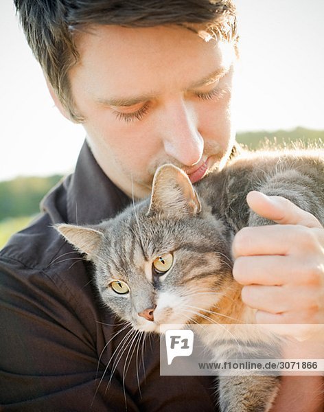 Eine junge Mann  der eine Katze Schweden hält.
