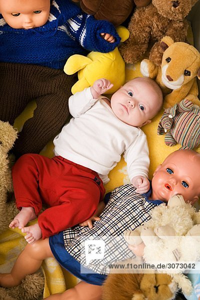 Ein Baby in einem Bett mit kuscheligen Spielzeug und Puppen Schweden
