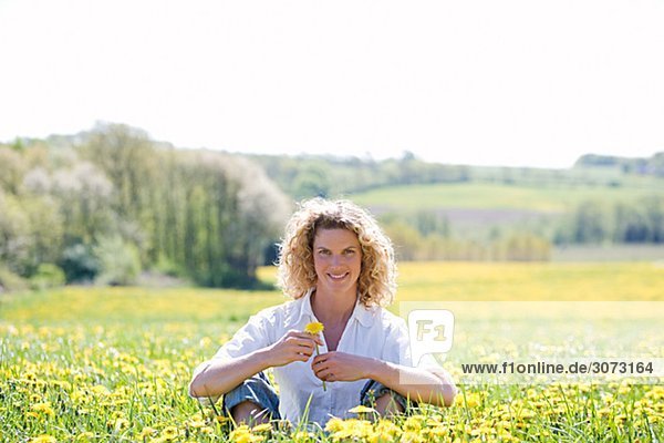 A woman sitting in a field of dandelions Sweden.