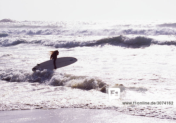 Frau mit Surfboard im Meer