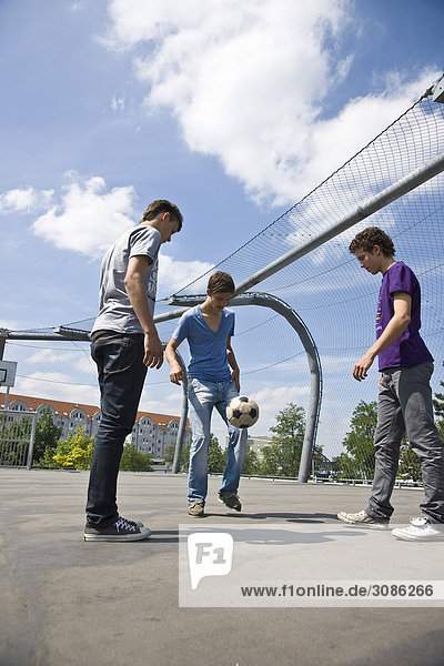 Drei Jungen spielen mit einem Fußball  Flachwinkelansicht