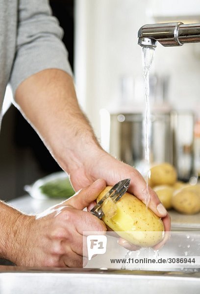 Mann schält Kartoffel