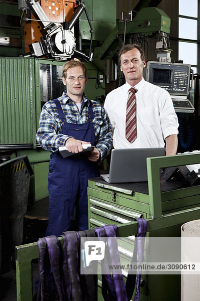 A factory manager and a factory worker in a metal parts factory