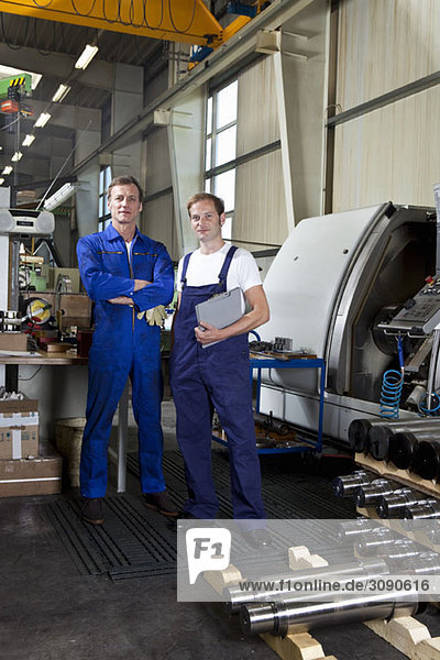 Portrait of two manual workers in a metal parts factory
