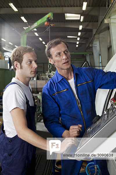 Two manual workers talking and working in a factory