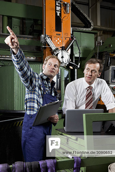 A factory manager and a factory worker in a metal parts factory