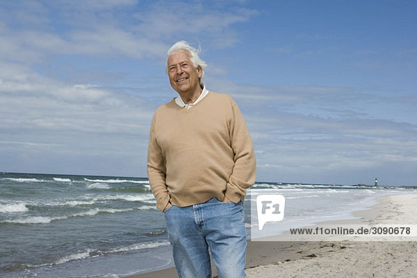 Ein älterer Mann  der am Strand steht.