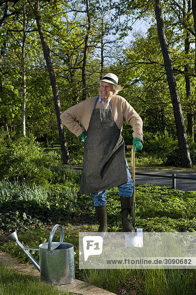 Ein älterer Mann  der eine Pause von der Gartenarbeit macht.