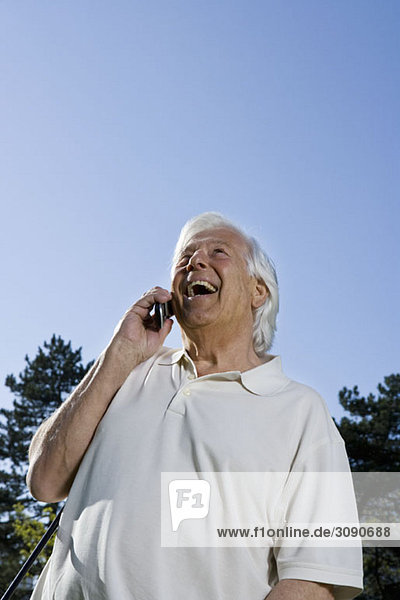 Ein älterer Mann  der ein Handy benutzt  im Freien.