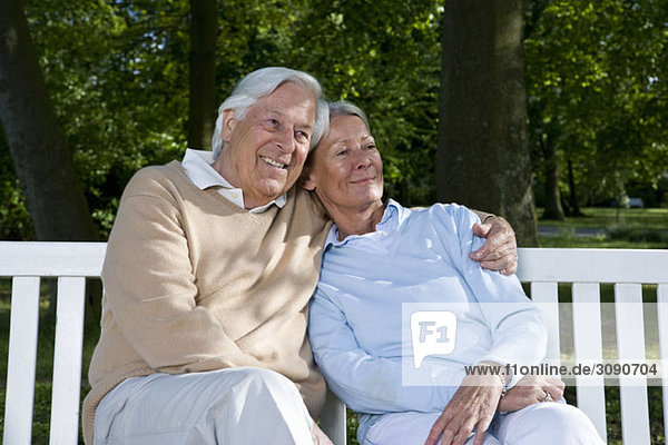 A senior couple sitting on a bench together