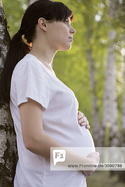 Eine schwangere Frau  die ihren Bauch hält  draußen.