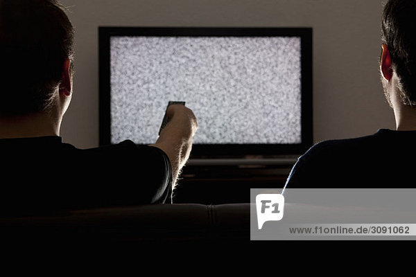 Two men watching static on television