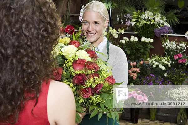 Eine Frau  die Blumen in einem Blumenladen kauft.