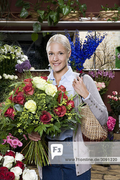 Eine Frau  die einen Rosenstrauß in einem Blumenladen hält.