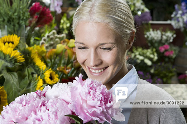 Eine Frau  die auf einen Blumenstrauß schaut und lächelt.