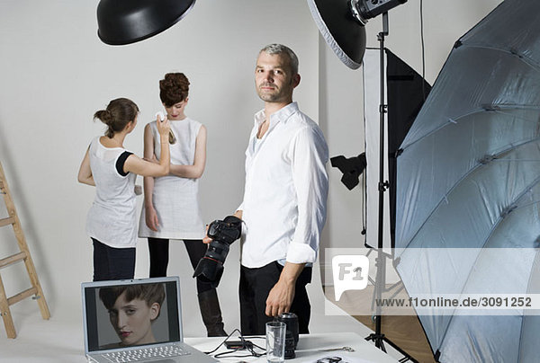 A photographer  model and make-up artist on set of a fashion shoot