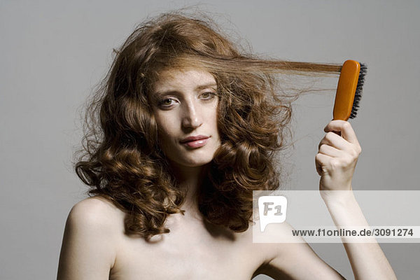 Eine junge Frau  die sich die Haare bürstet.
