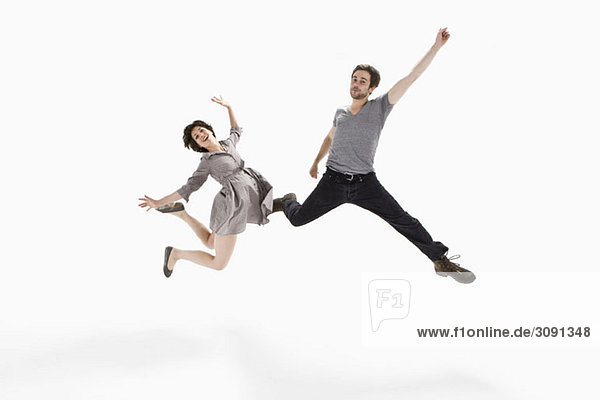 A young man and a young woman jumping mid-air