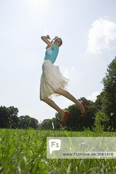 Eine junge Frau  die auf einem Feld springt.