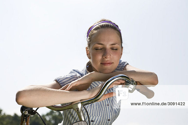 Eine junge Frau  die sich auf den Fahrradlenker stützt.