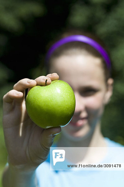 Eine Frau  die einen grünen Apfel ausstreckt.