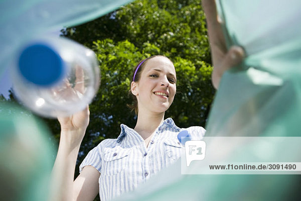 Eine Frau  die eine Plastikflasche wegwirft.