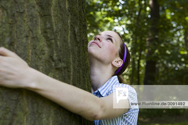 Eine junge Frau  die einen Baum umarmt.