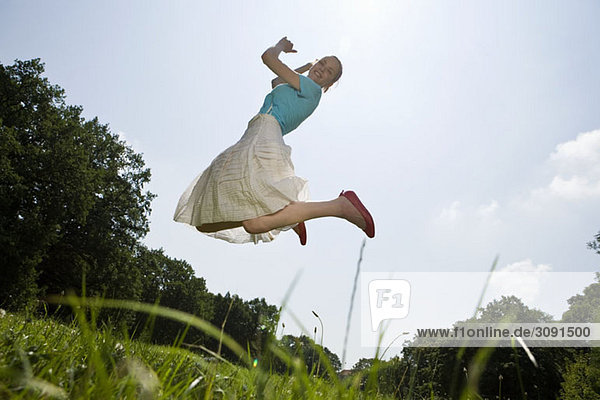 Eine junge Frau  die auf einem Feld springt.
