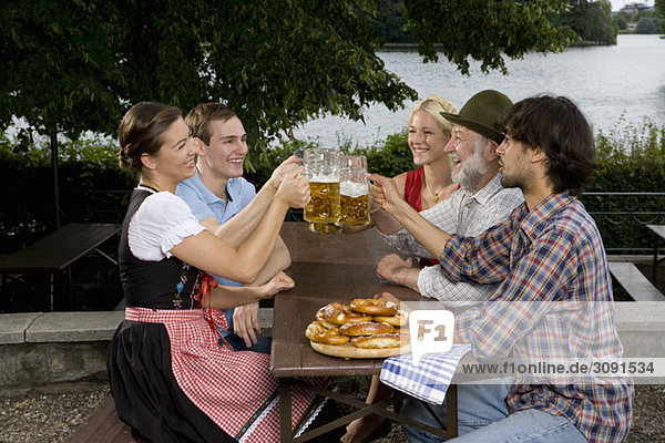 Fünf Personen in einem Biergarten Toastgläser