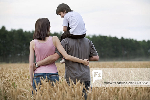 A young family walking through a wheat field