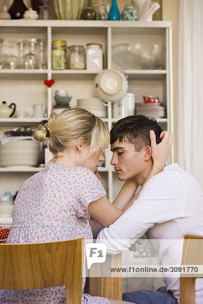 Ein junges  leidenschaftliches Paar  das in einer heimischen Küche sitzt.
