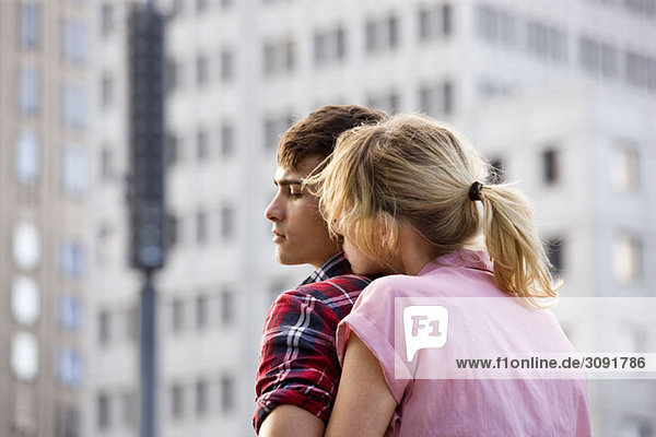 A young couple embracing in an urban setting