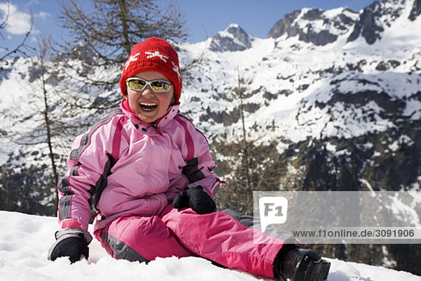 Girl in pink sitting in the snow.