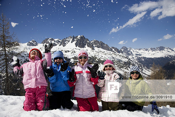 5 kids kneeling throwing snow.
