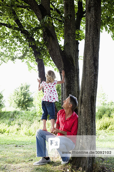 Vater und Tochter klettern auf dem Baum