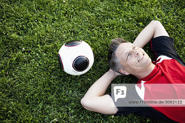 Fußballspieler entspannt auf dem Rasen