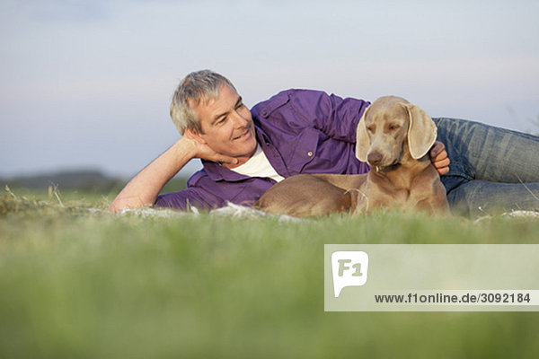 man with dog lying on the grass smiling