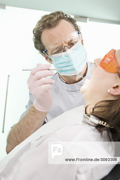Ein Zahnarzt  der einen Patienten untersucht.
