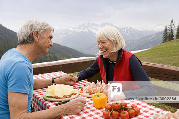 Seniorenpaar beim Essen in den Bergen