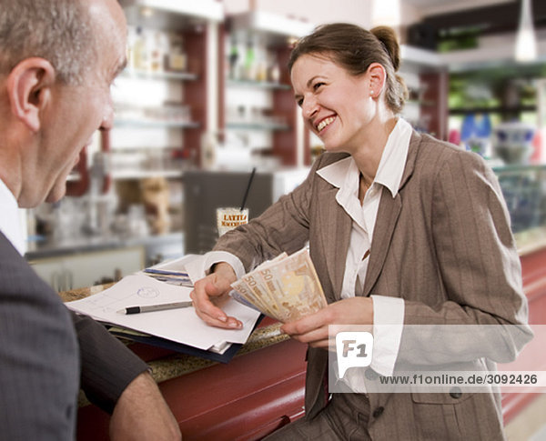 Geschäftsfrau bezahlt Mann in der Bar