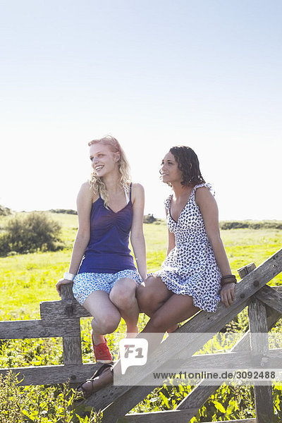 zwei Mädchen auf einem Zaun sitzend