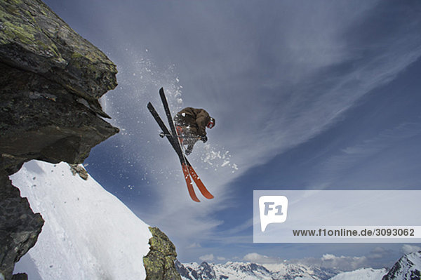 Skifahrer  der von einem Felsen springt.