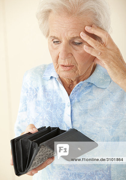 Seniorin schaut erschrocken in leere Geldbörse