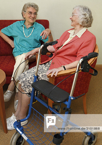 Zwei Seniorinnen unterhalten sich  Gehwagen steht daneben