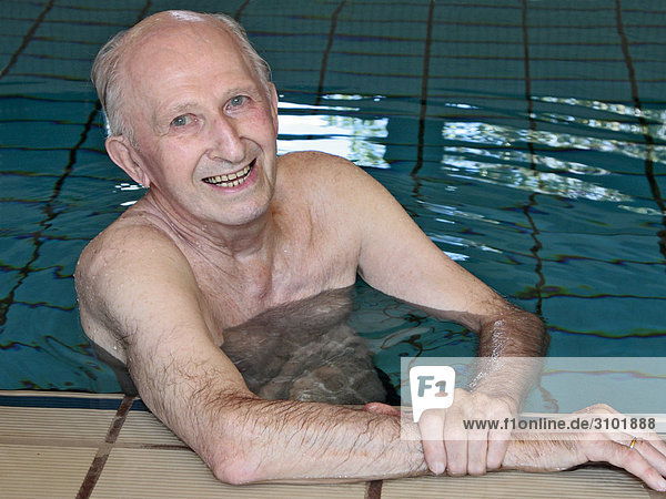 Senior in Hallenbad im Schwimmbecken  lacht