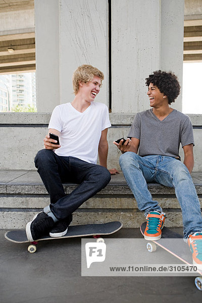 Teenage boys with cellphones and skateboards