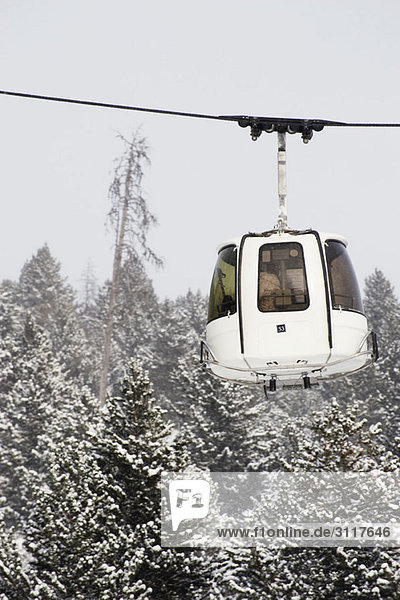 Luftseilbahn fährt an schneebedeckten Bäumen vorbei