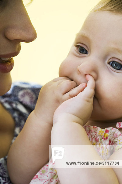 Mutter hält Kleinkind mit Fingern im Mund